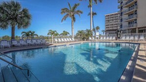 Ein klares Schwimmbecken mit Liegestühlen und Palmen.