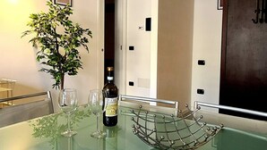 A modern dining area with a glass table, chairs, a bottle of wine, and a small potted plant. - Casa il Cielo (Polpenazze del Garda)