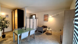 A compact living space with a glass dining table, a sofa, a small side table, and a potted plant. - Casa il Cielo (Polpenazze del Garda)