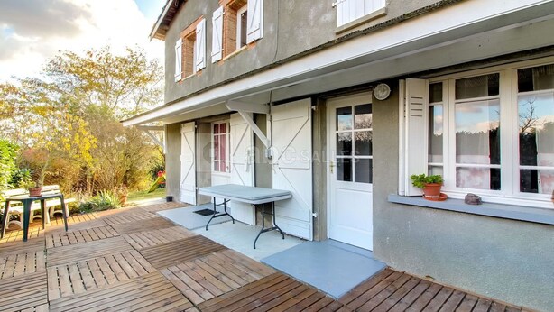 A two-story house with a patio area featuring a table and chairs. - Group Lodging and Event Space: La Ferme d'Odette (Poucharramet)