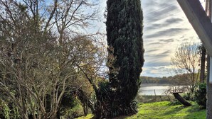 A garden with a lawn, a tall tree, and a body of water in the background. - Group Lodging and Event Space: La Ferme d'Odette (Poucharramet)