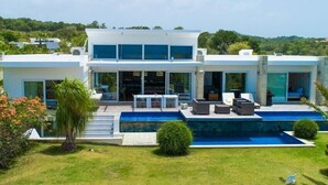 A modern two-story house with a swimming pool, outdoor seating, and a lush garden. - V12 Casa Summerhill  · Luxury villa w/ 2-level pool + bar and pool table (Sosúa)