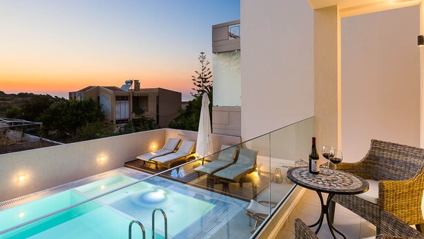 Un espace piscine aménagé sur le toit, avec des chaises longues et une table sur laquelle sont disposés des verres à vin et une bouteille.