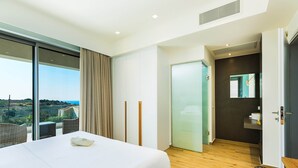 Une chambre d’hôtel moderne dotée d’un grand lit, offrant une vue sur la ville, comprenant une salle de bain avec un miroir et un plancher en bois.