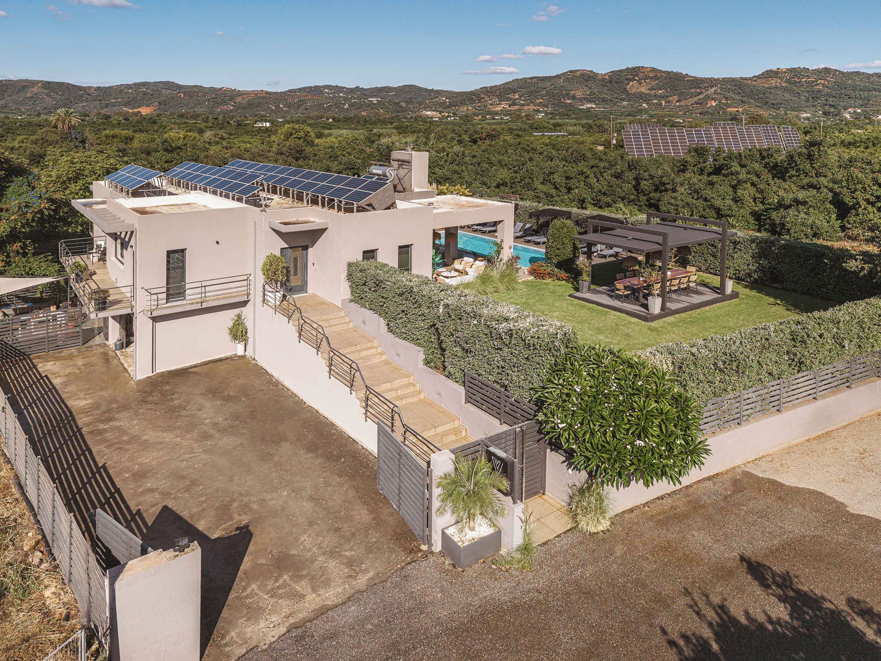 A modern house with solar panels, a swimming pool, and a patio area.