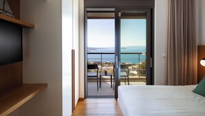 A hotel room with a balcony, a bed, a TV, and a view of the sea. - Omnia Villa II - Heated* pool & dazzling seaview! (Chania)