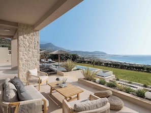 Eine Terrasse mit Gartenmöbeln, einem Pool und Blick auf das Meer und die Berge.