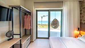 Ein Schlafzimmer mit Bett, Schreibtisch, Hängekorbschaukel und Blick auf den Strand.
