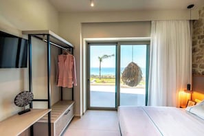 Ein Schlafzimmer mit Bett, Schreibtisch, Hängekorbschaukel und Blick auf den Strand.
