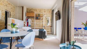 Una habitación con pared de piedra, cama, escritorio, silla, mesa y vistas al exterior.