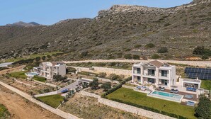 Un moderno resort con varias villas, piscina y paneles solares.