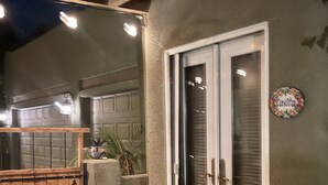 A modern entrance with a sliding glass door, a wooden gate, and a doormat. - Perfectly Located Fully Remodeled Desert Casita (Bermuda Dunes)