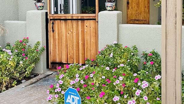 A wooden gate with a metal frame, a wooden door, and a blue sign with contact information. - Perfectly Located Fully Remodeled Desert Casita (Bermuda Dunes)