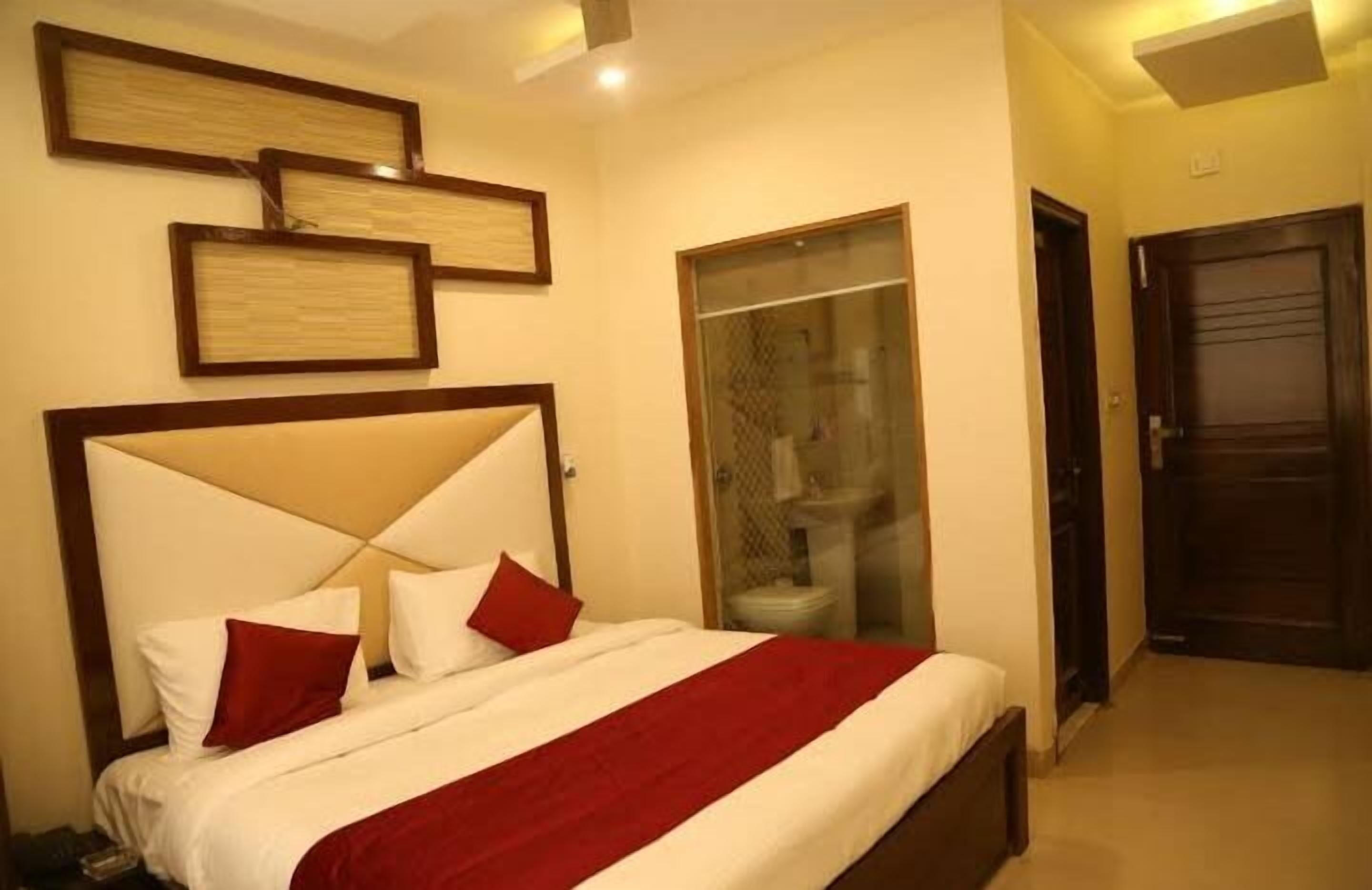 A hotel room with a bed, a wardrobe, and a bathroom visible through a glass door.