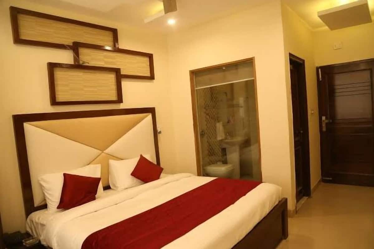A hotel room with a bed, a wardrobe, and a bathroom visible through a glass door.