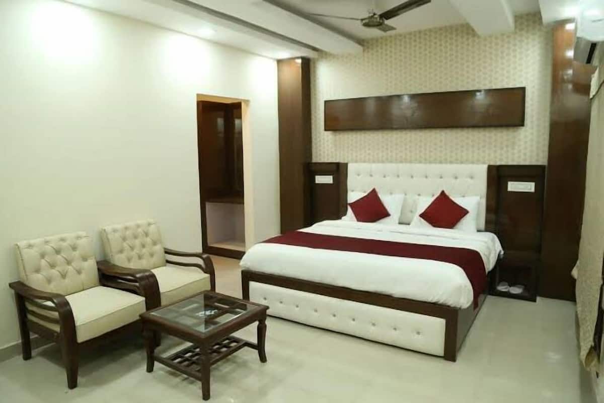 A hotel room with a large bed, two armchairs, a small table, and a ceiling fan.