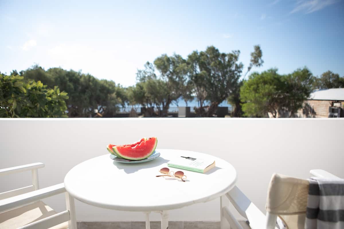 A round white table with a watermelon, a book, and sunglasses on it.