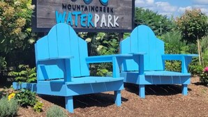 Señal para el parque acuático Mountaintop con dos sillones Adirondack azules al frente.