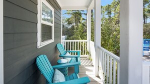 En veranda med to turkise Adirondack-stole, et lille rundt bord og et hvidt gelænder.