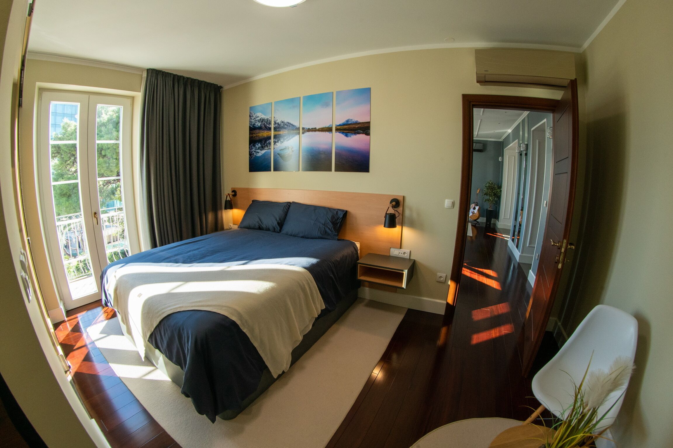 Une chambre à coucher avec un lit, des tables de chevet, une commode, une fenêtre avec des rideaux et une porte.