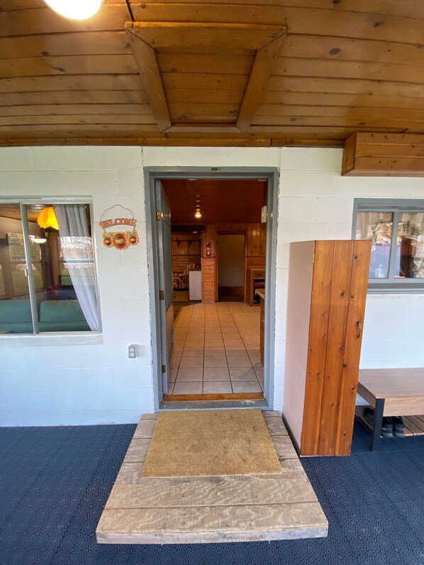 A wooden interior with a tiled floor, a welcome sign, and a bench.
