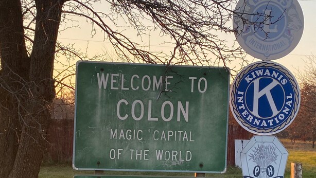 Willkommensschild für Colon, Missouri, mit dem K-State International Logo und einem Schild für die Lutherische Kirche.