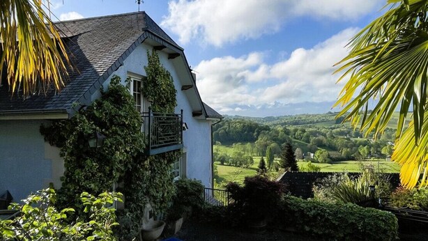 A house with a sloped roof, ivy-covered walls, and a view of a green landscape. - Le Belvue, a relaxing stay with a view of the Pyrenees mountain range  (ESTIALESCQ)