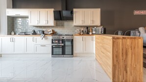 Una cocina moderna con armarios blancos, encimera de madera, horno empotrado y estufa negra.