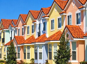 Een rij kleurrijke herenhuizen met rode dakpannen en witte raamkozijnen.