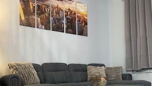 Un salon moderne avec un canapé gris, une table basse en verre et un tapis à motifs.
