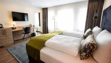 A hotel room with a bed, desk, chair, TV, and curtains.