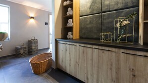 Una cocina moderna con un armario de madera, una pared acolchada negra y un estante con toallas enrolladas.