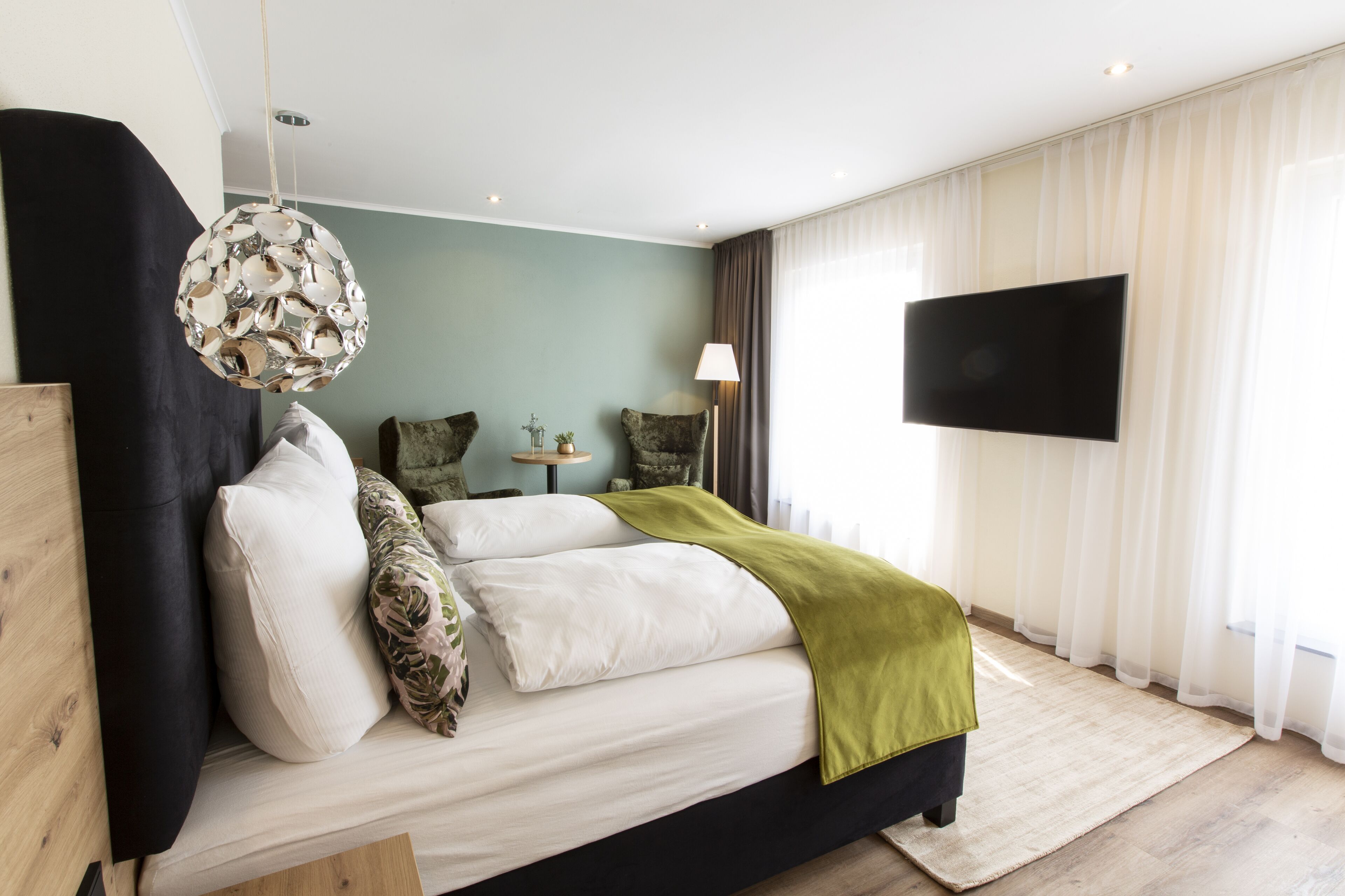 A modern bedroom with a bed, a television, and a unique hanging light fixture.