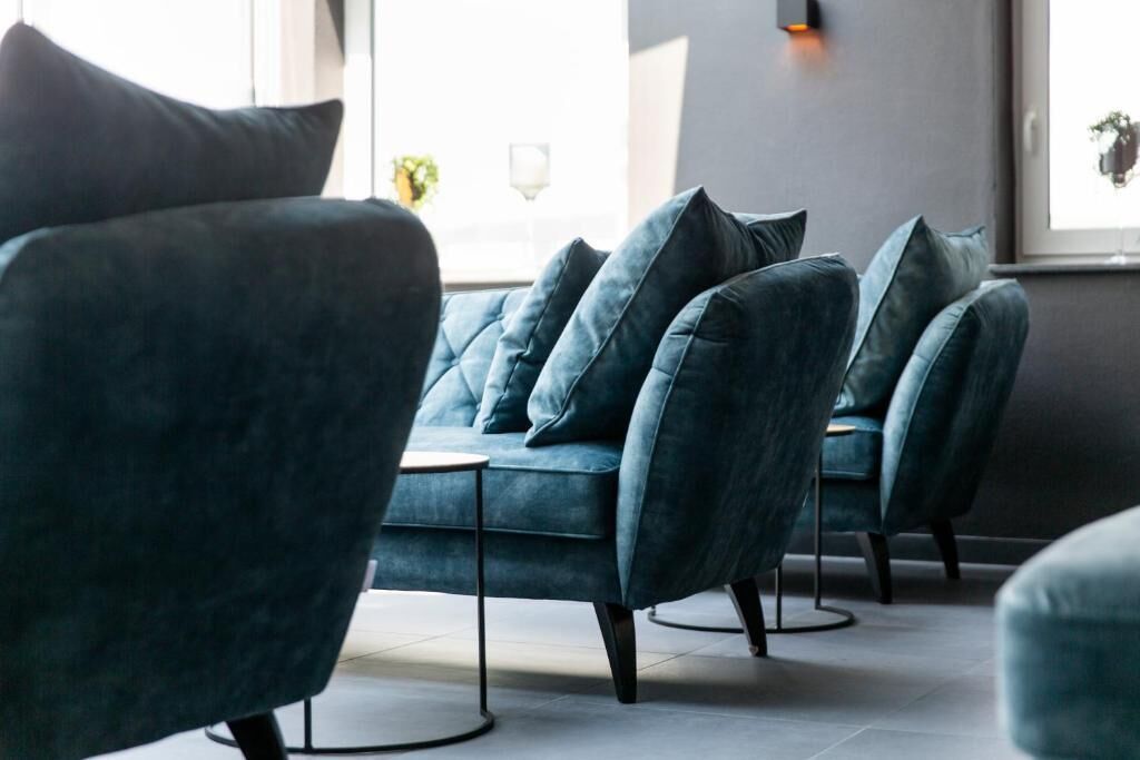 A modern lounge area with a sofa and chairs, a small table, and a window with a view.