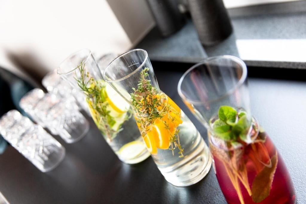 Tre glas vatten med citronskivor och örter.