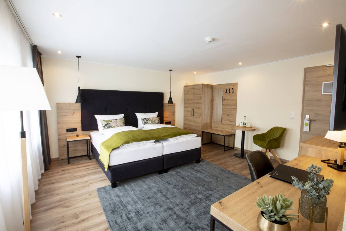 Ein modernes Hotelzimmer mit einem großen Bett, einem Schreibtisch, einem Stuhl, einem Fernseher und einem Kleiderschrank.
