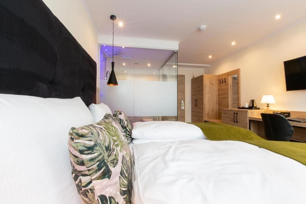 A modern hotel room with a large bed, a desk, and a TV.