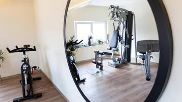 A home gym with exercise equipment, a window, and a plant.