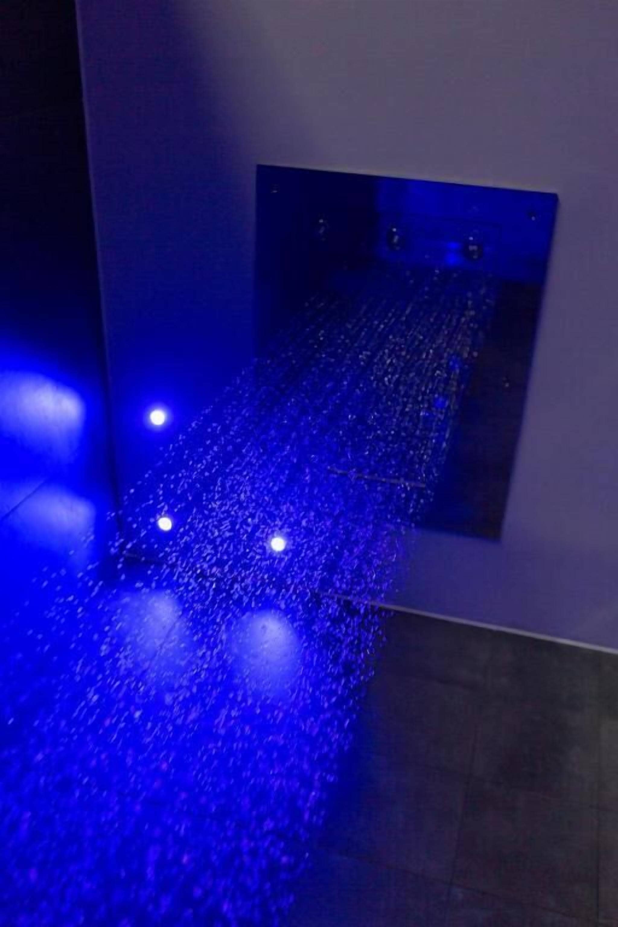 Un pasillo con una instalación de luz azul y un panel oscuro en la pared.