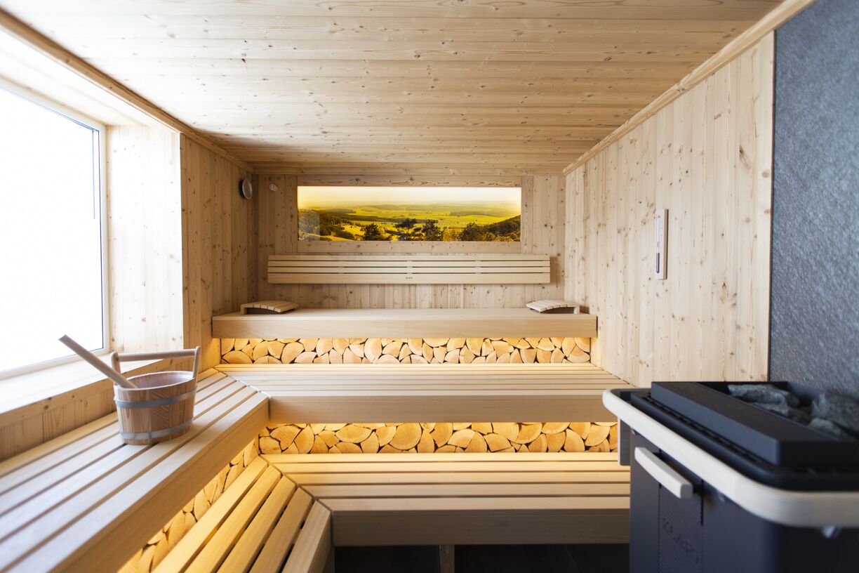 A sauna with wooden benches and a view of a landscape through a window.