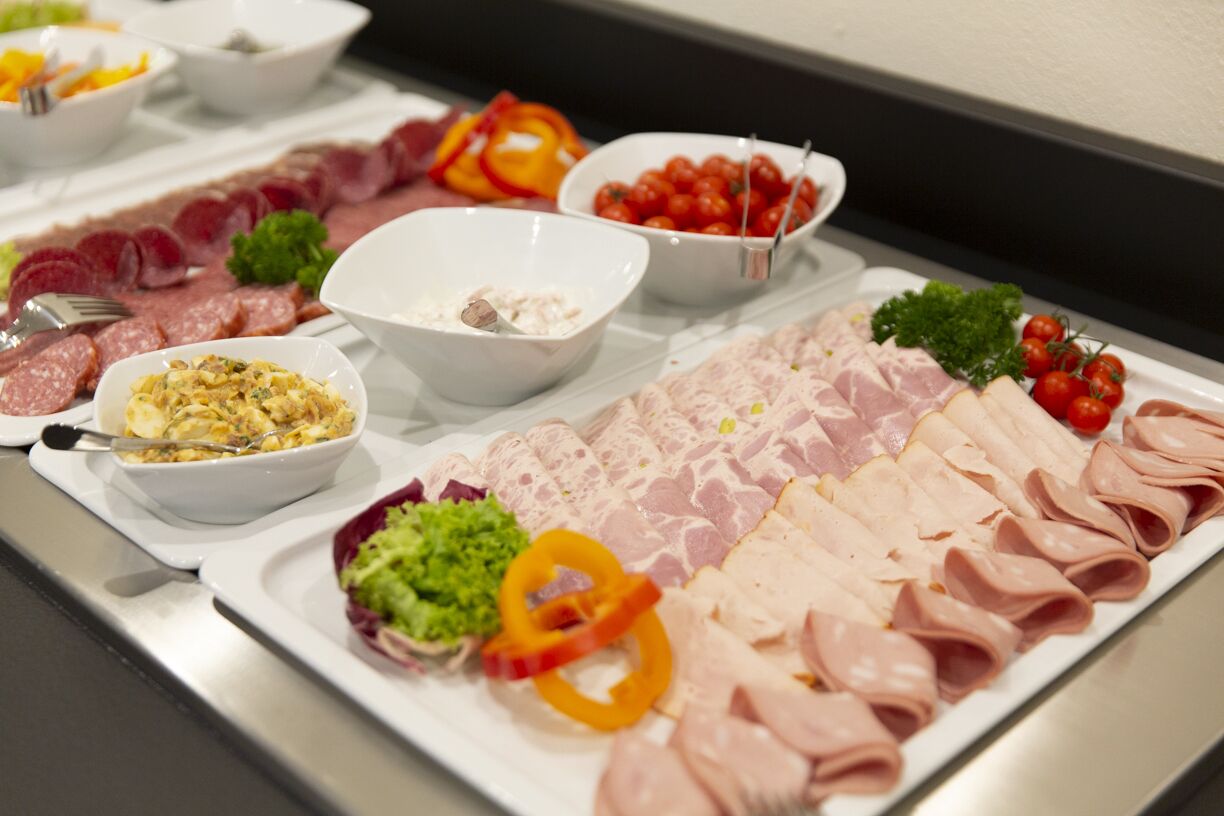 A buffet with various meats, salads, and condiments.