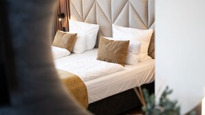 Una cama bien hecha con sábanas blancas y varios almohadones, incluyendo un plaid decorativo.