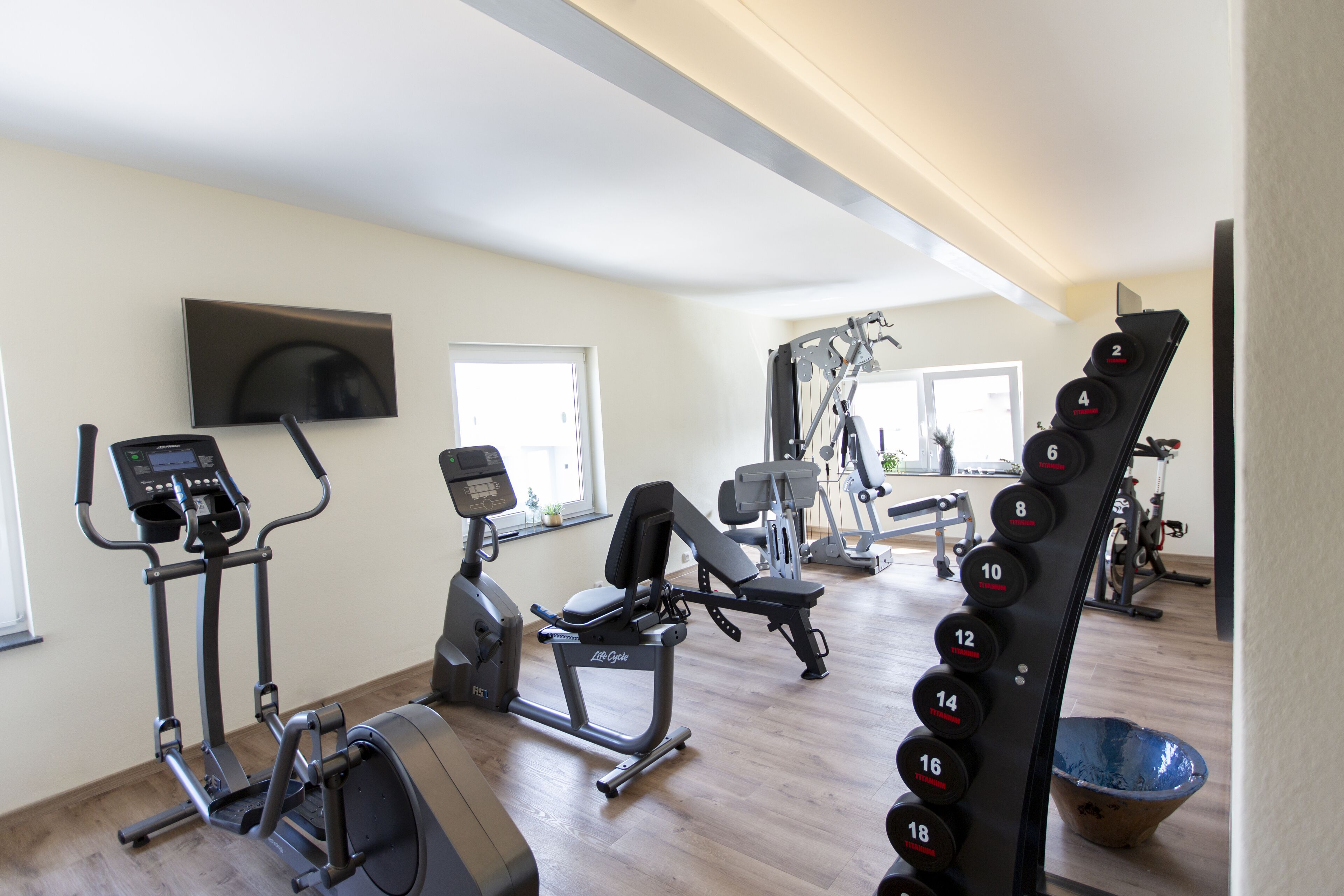 A gym with various exercise equipment, including treadmills, an elliptical, and a weight bench.