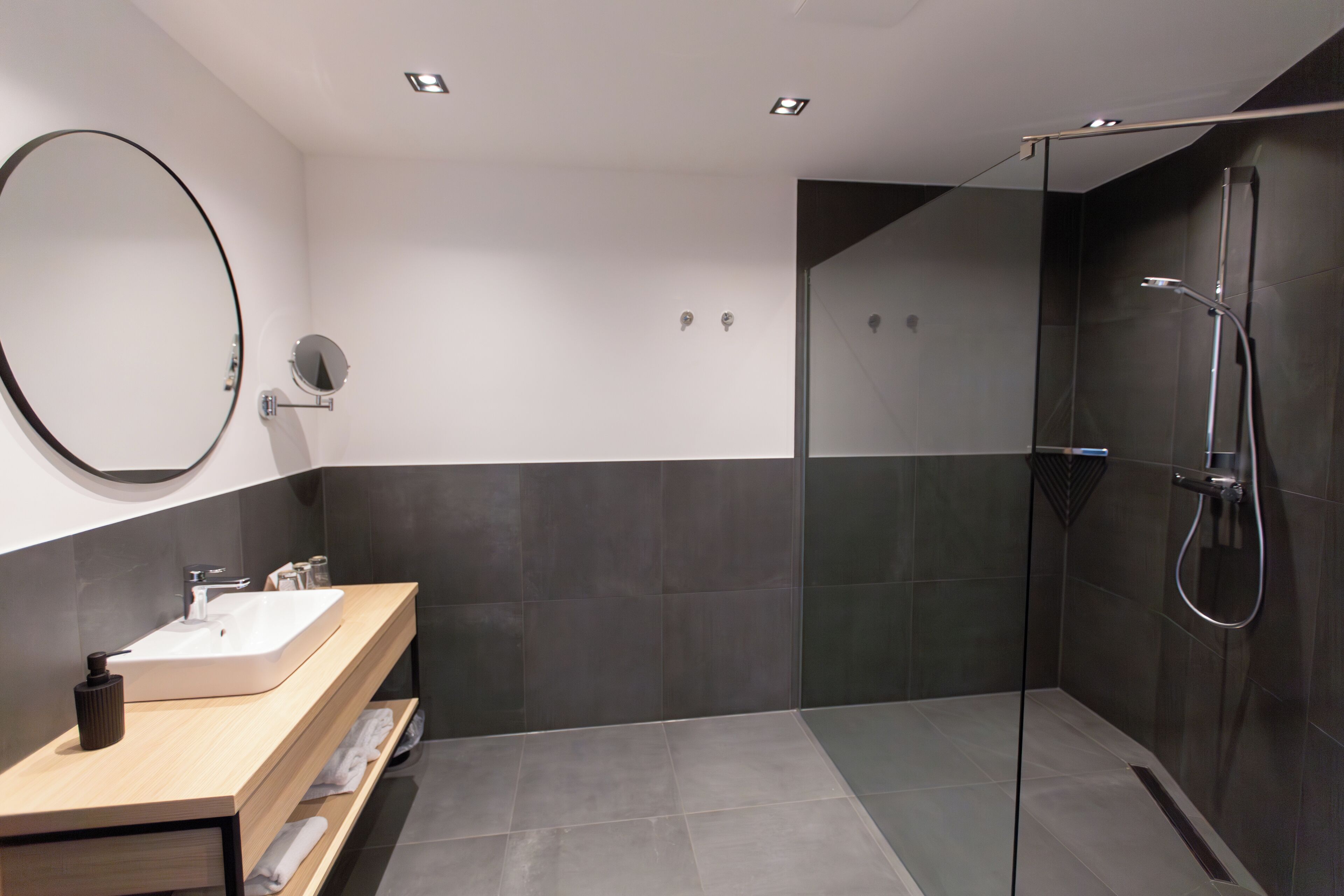 Een moderne badkamer met een grote spiegel, een wastafel en een douchehoek.