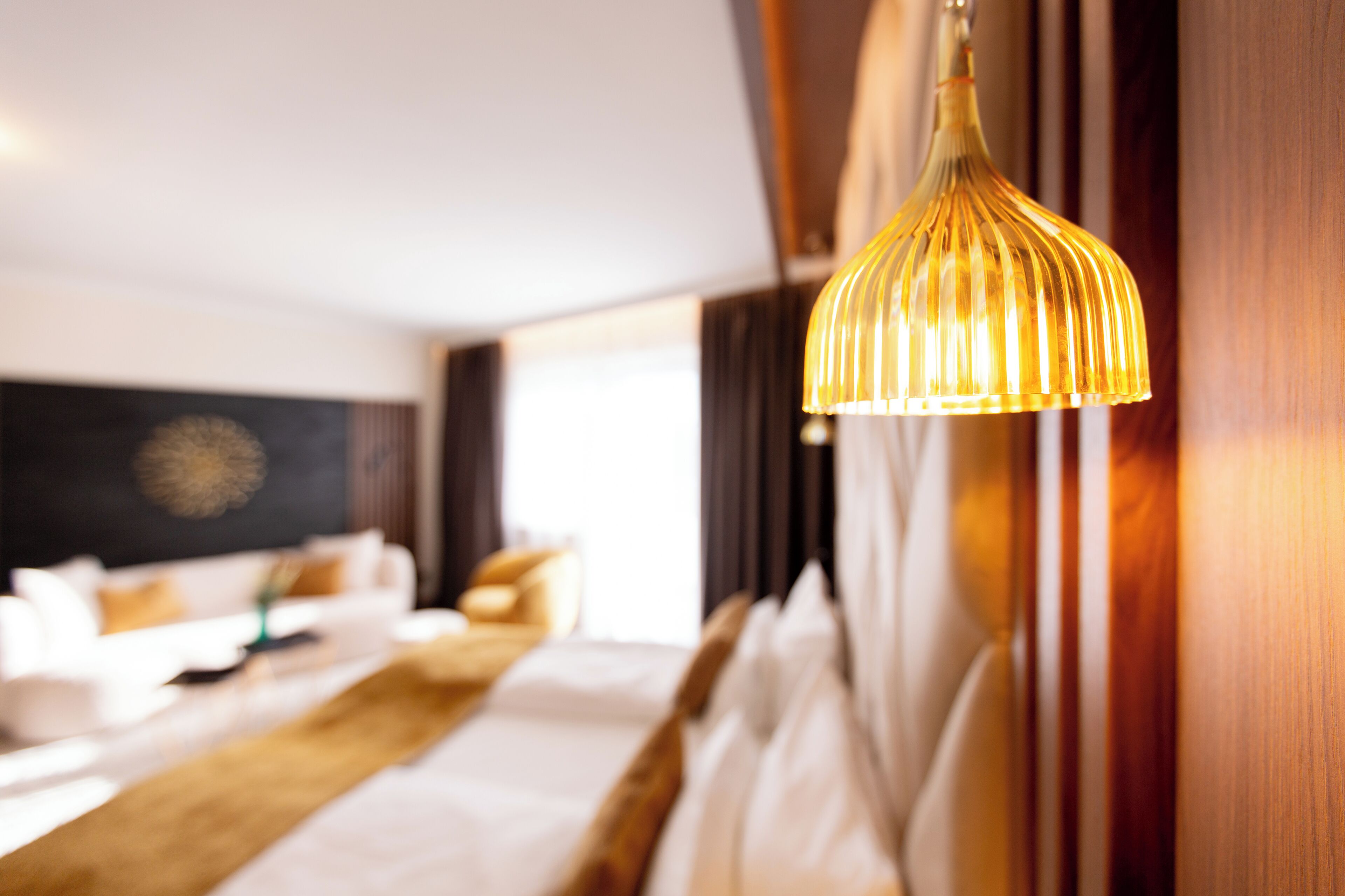 A hotel room with a bed, a bedside table, and a hanging lamp.