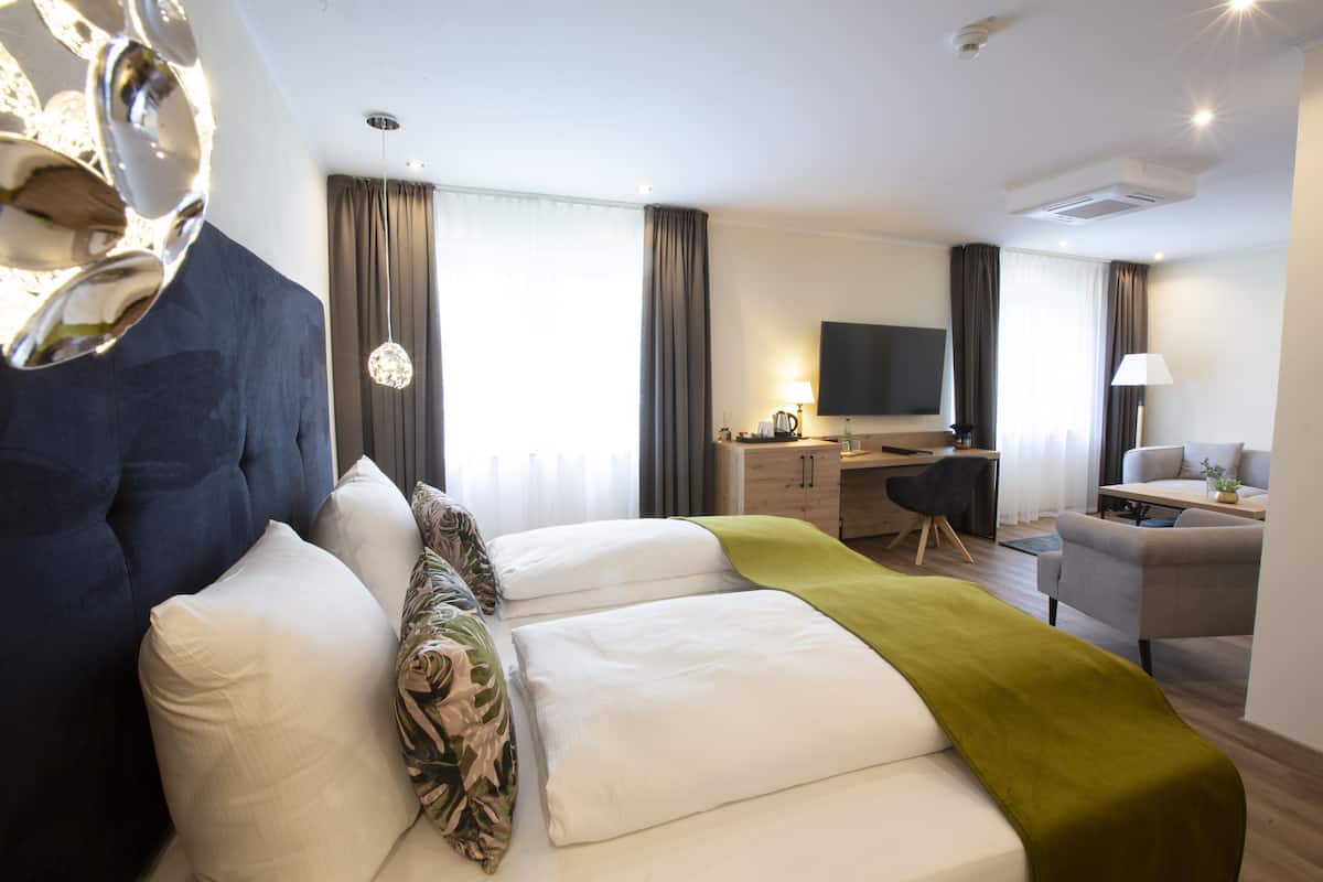 Ein modernes Hotelzimmer mit einem großen Bett, einem Schreibtisch, einem Fernseher und einer Sitzecke.
