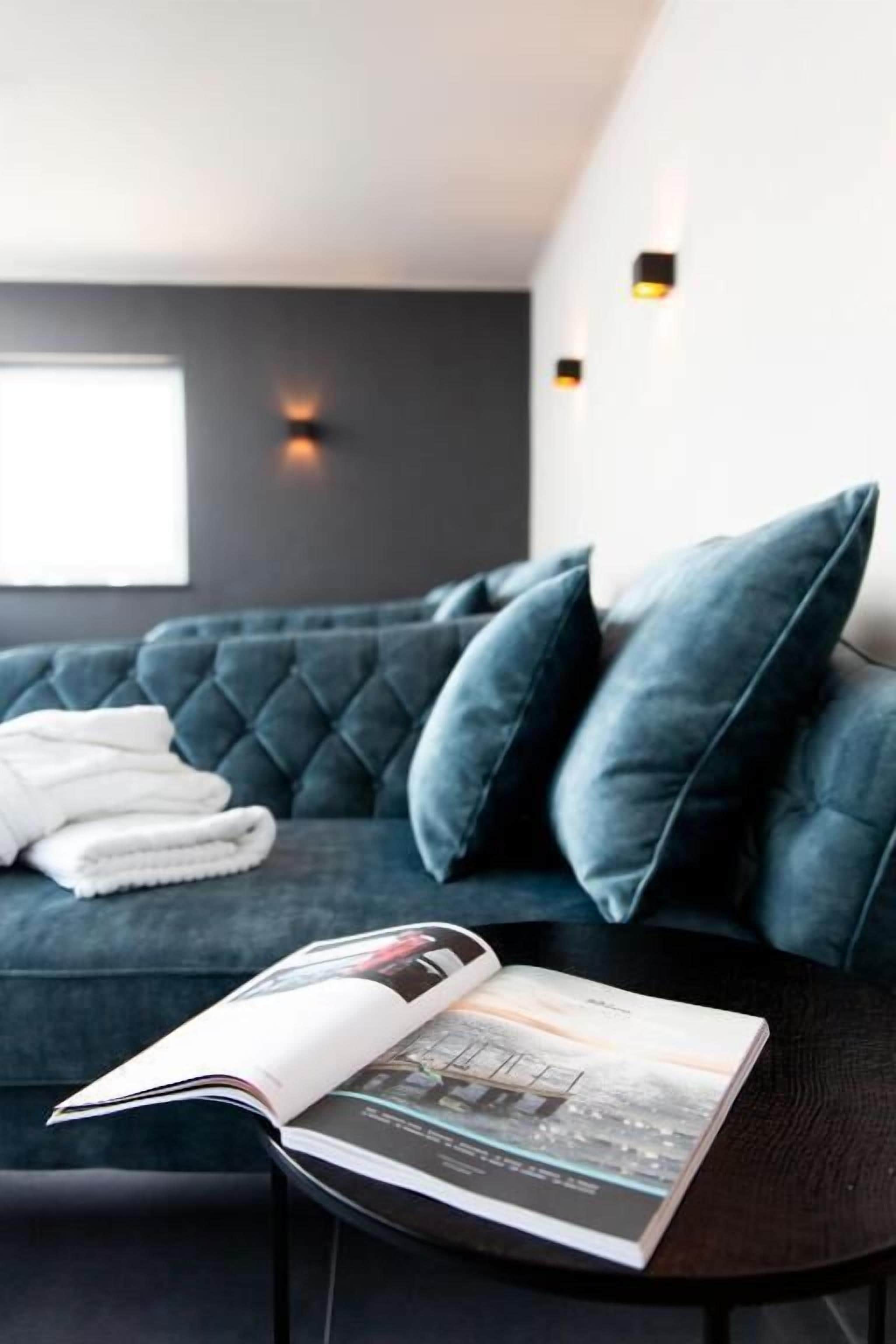 A dark blue sofa with a magazine on a small round table.