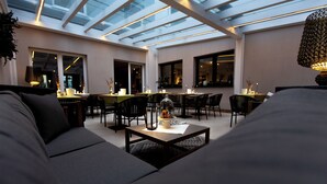 Un interior moderno con techo de vidrio, un sofá, una mesa de comedor con sillas y una lámpara decorativa.