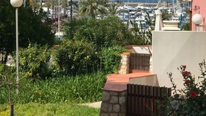 A marina with boats, a building with balconies, and a view of the sea.