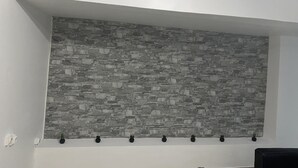 Ein Zimmer mit einer Wandverkleidung aus Stein, einer weißen Decke und einer schwarzen Bank.